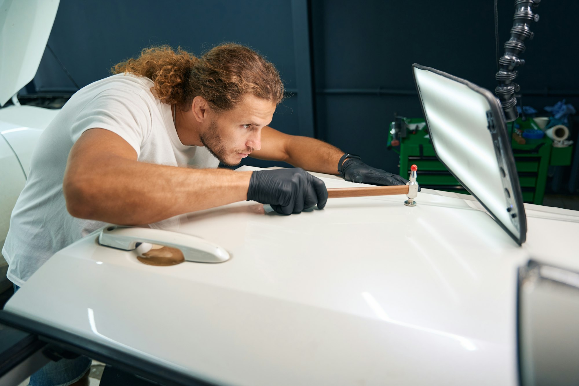 Man levels out dents in the body of white car